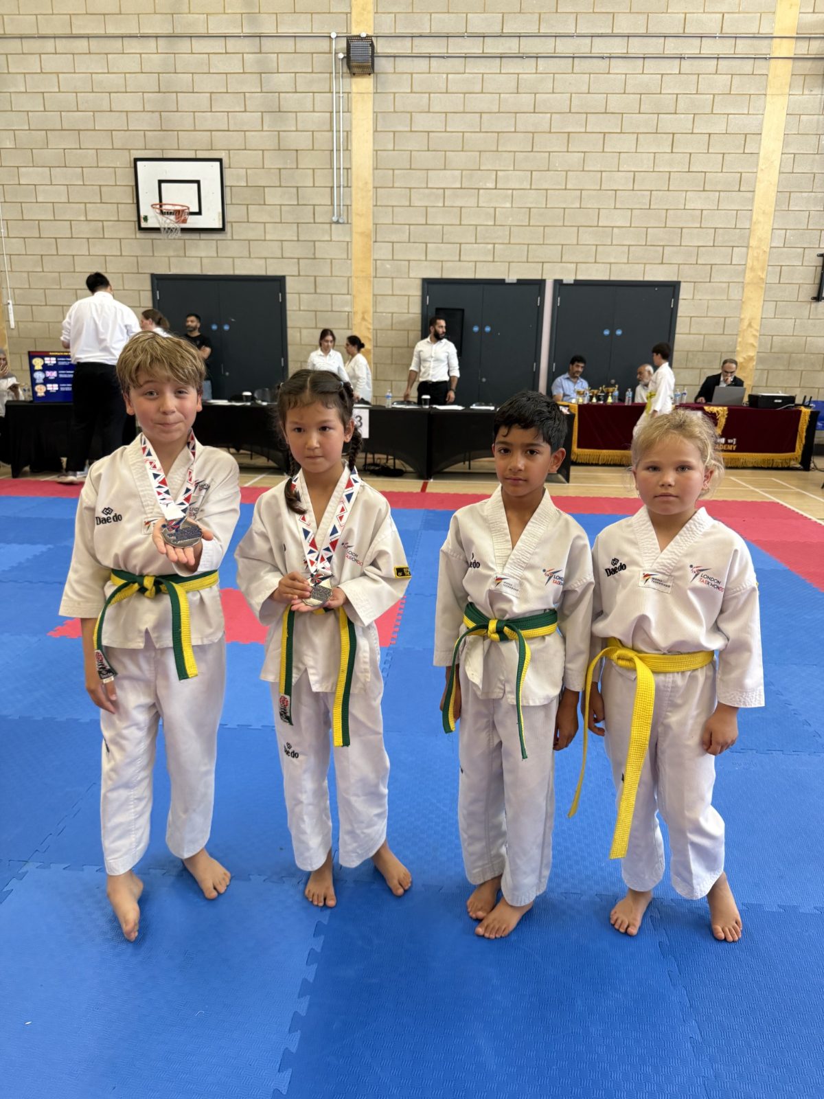 Four students with their medals on the mat