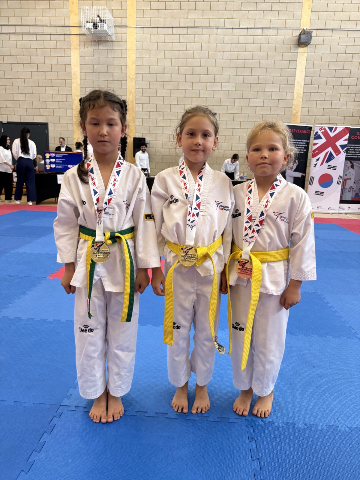 Three young students wearing gold and bronze medals