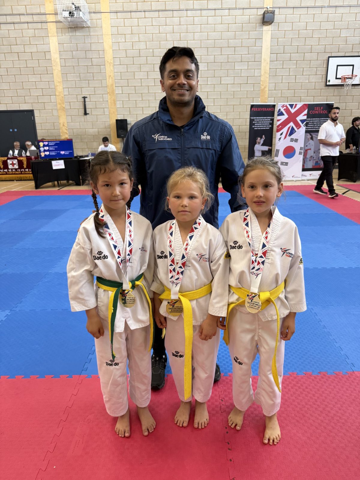 Three Little Panthers with gold medals beside the head coach