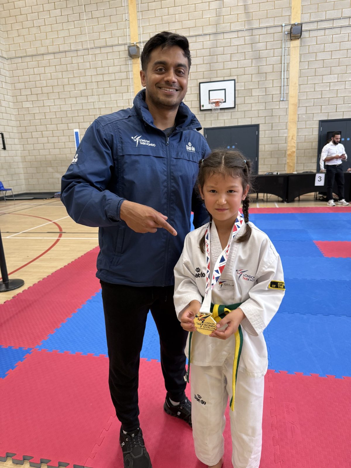 Young student with a gold medal beside the head coach