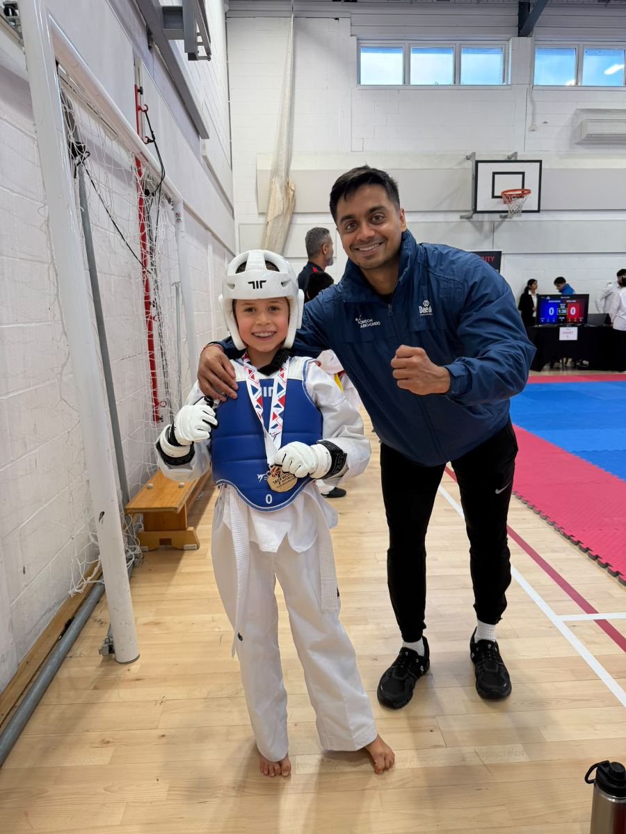 Smiling student in a white head guard with a gold medal