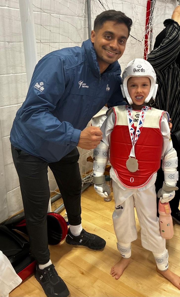 Student in red sparring kit with a silver medal