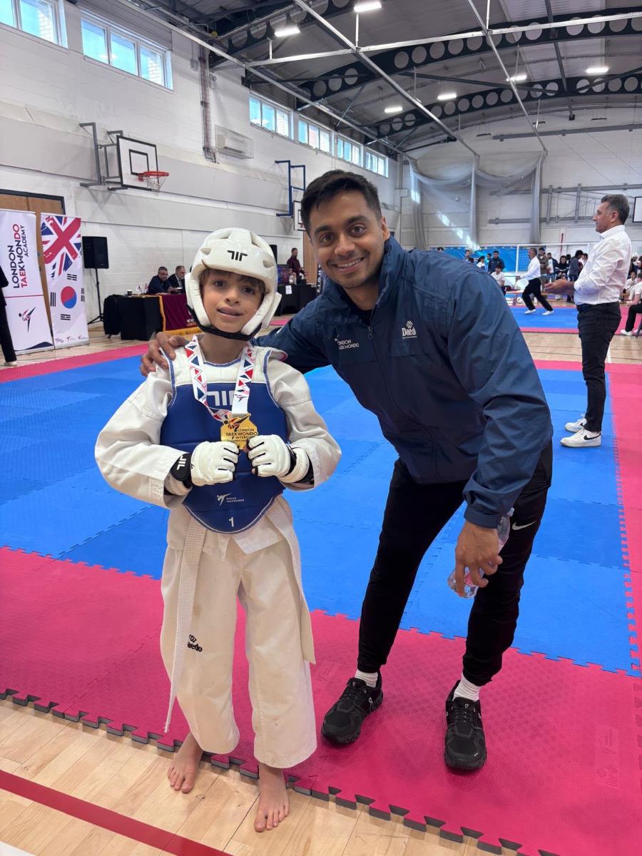 Student in a white head guard holding a gold medal
