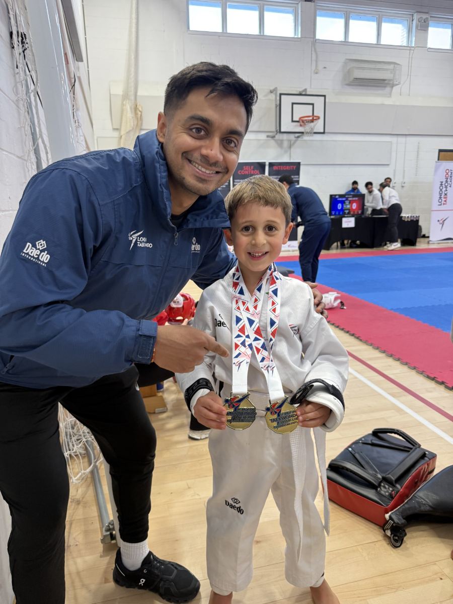 A Little Panther with two gold medals beside the head coach